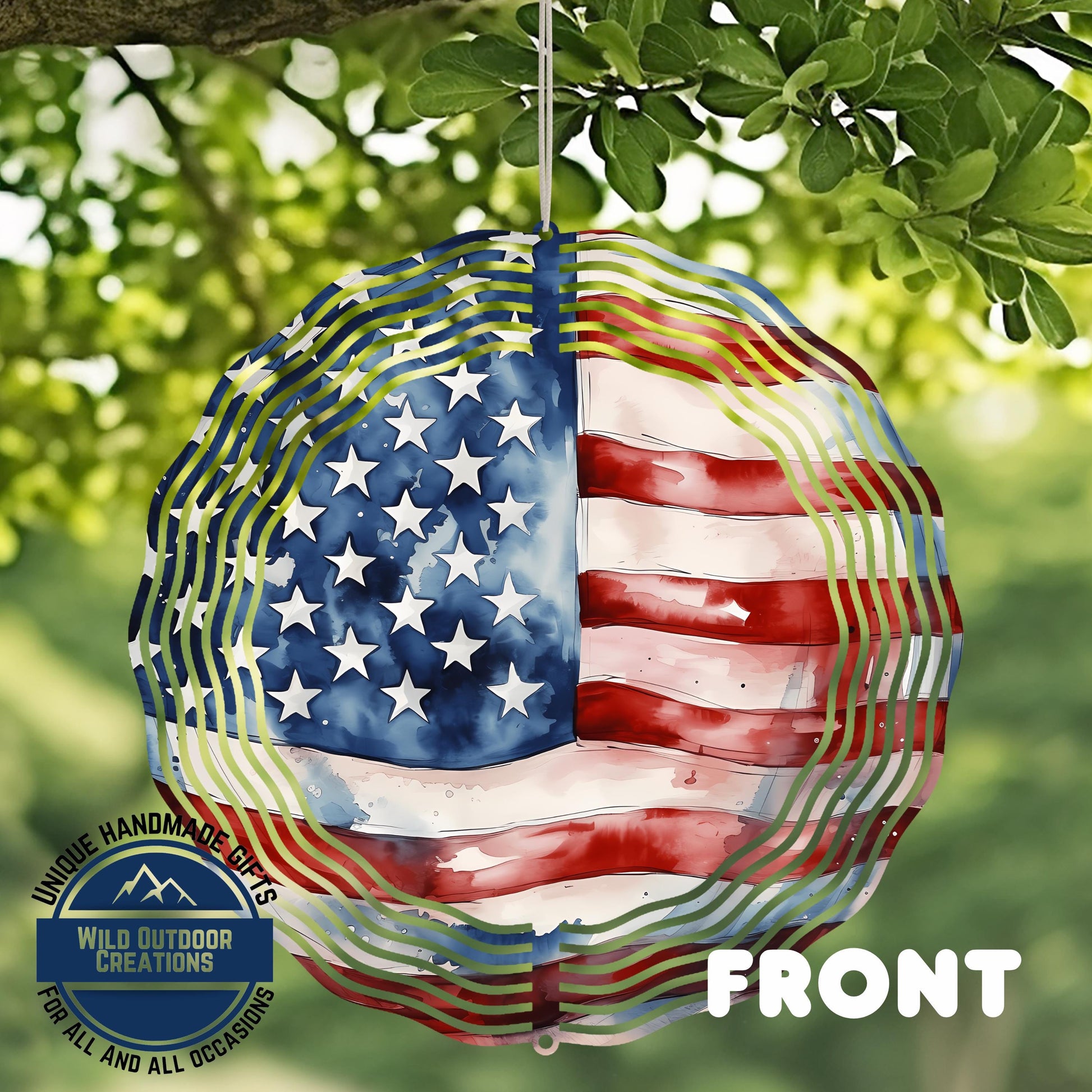 a wind chime with an American flag design, hanging in a natural outdoor setting with green foliage in the background.